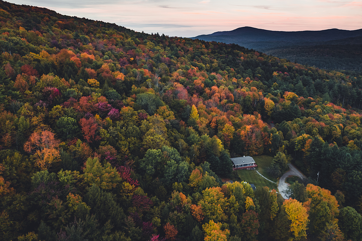 House nestled at the bottom of a hill in Vermont during fall with beautiful leaves changing colors