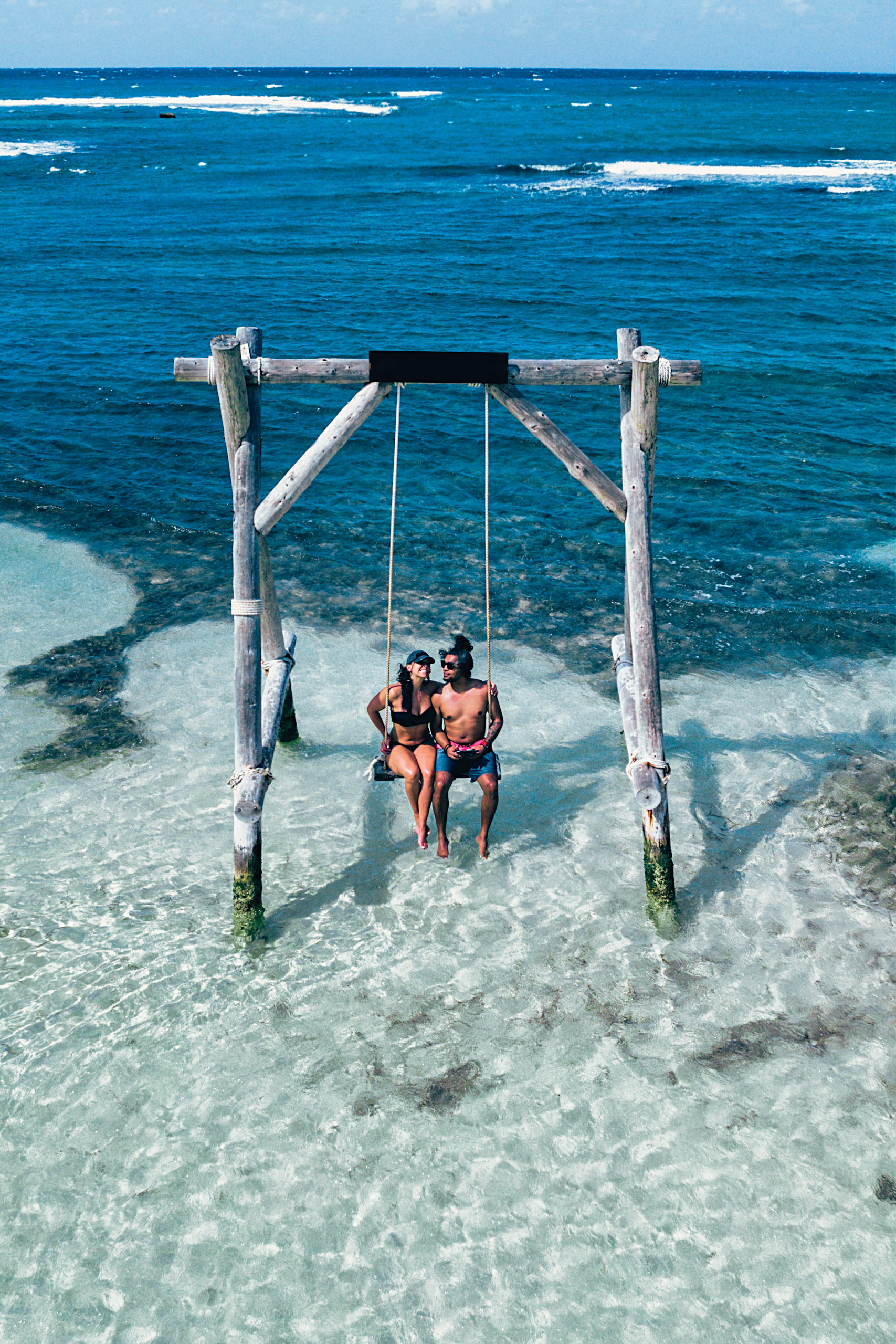 Dan and Emily Mall on a swing in the ocean