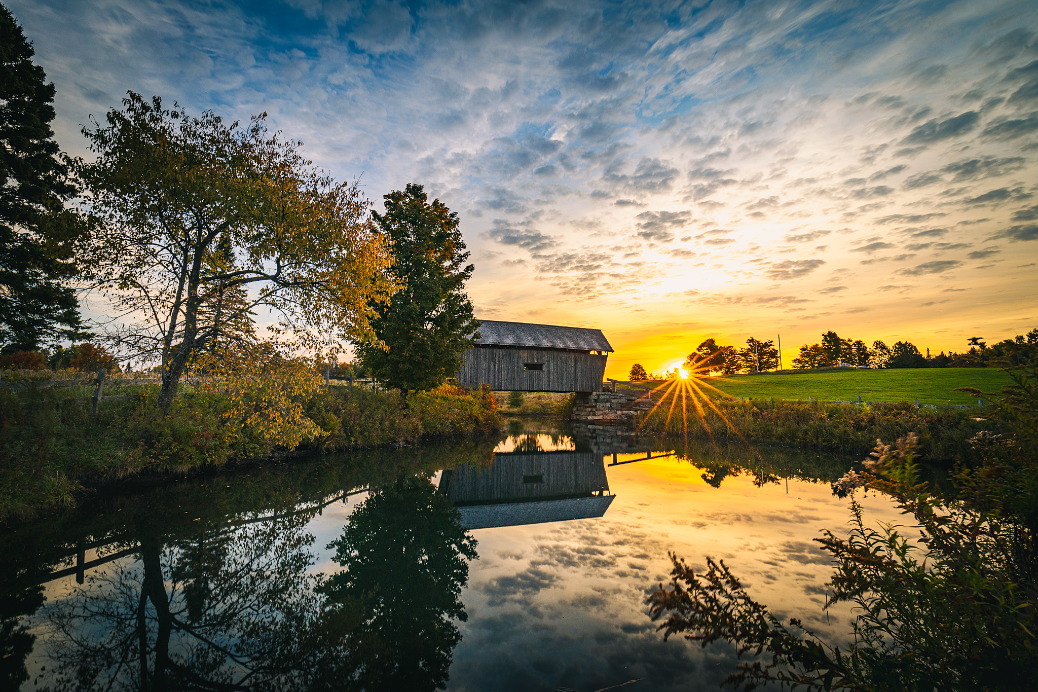 The A.M. Foster Covered Bridge at sunrise with its reflection in a pond