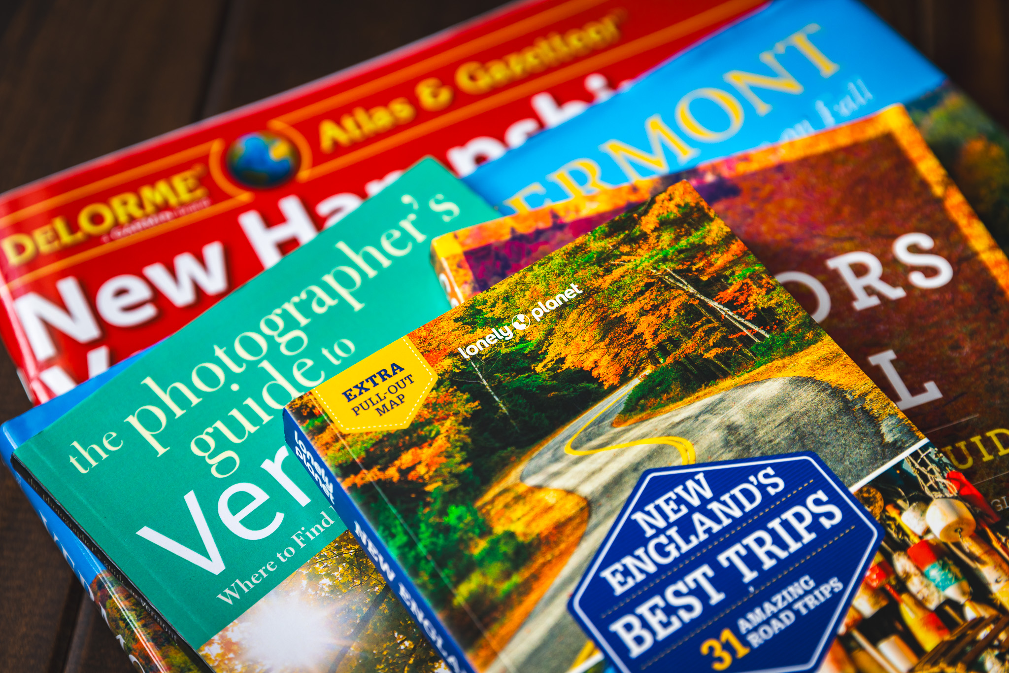 A stack of photography books like “New England’s Best Trips,” “The Photographer’s Guide to Vermont,” Colors of the Fall,” and more