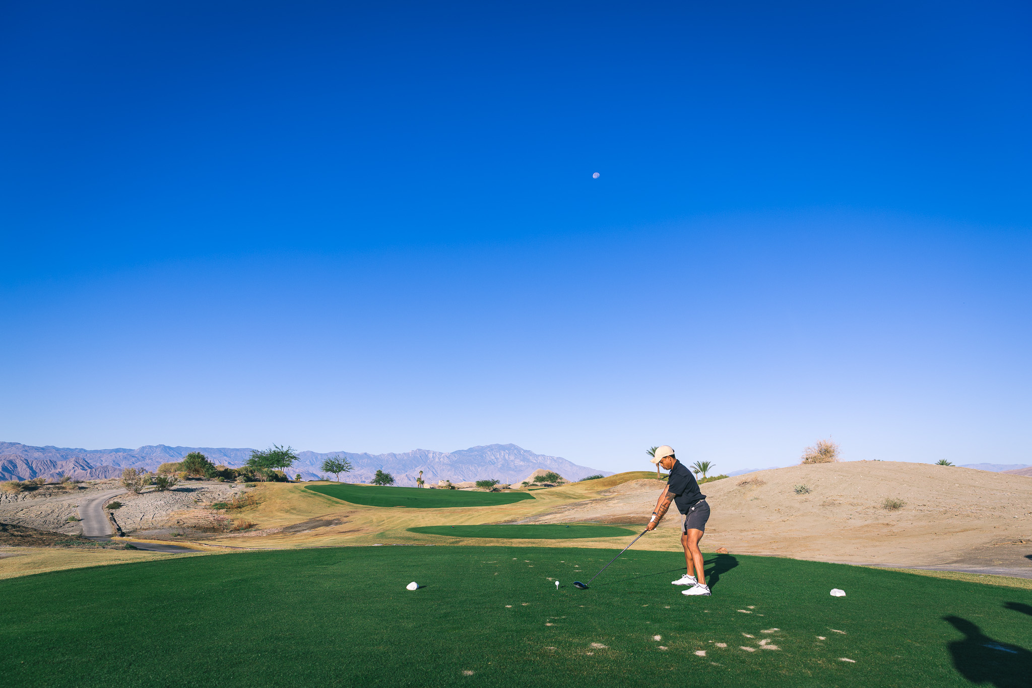 Golfer lining up a tee shot with beautiful mountains in the distance