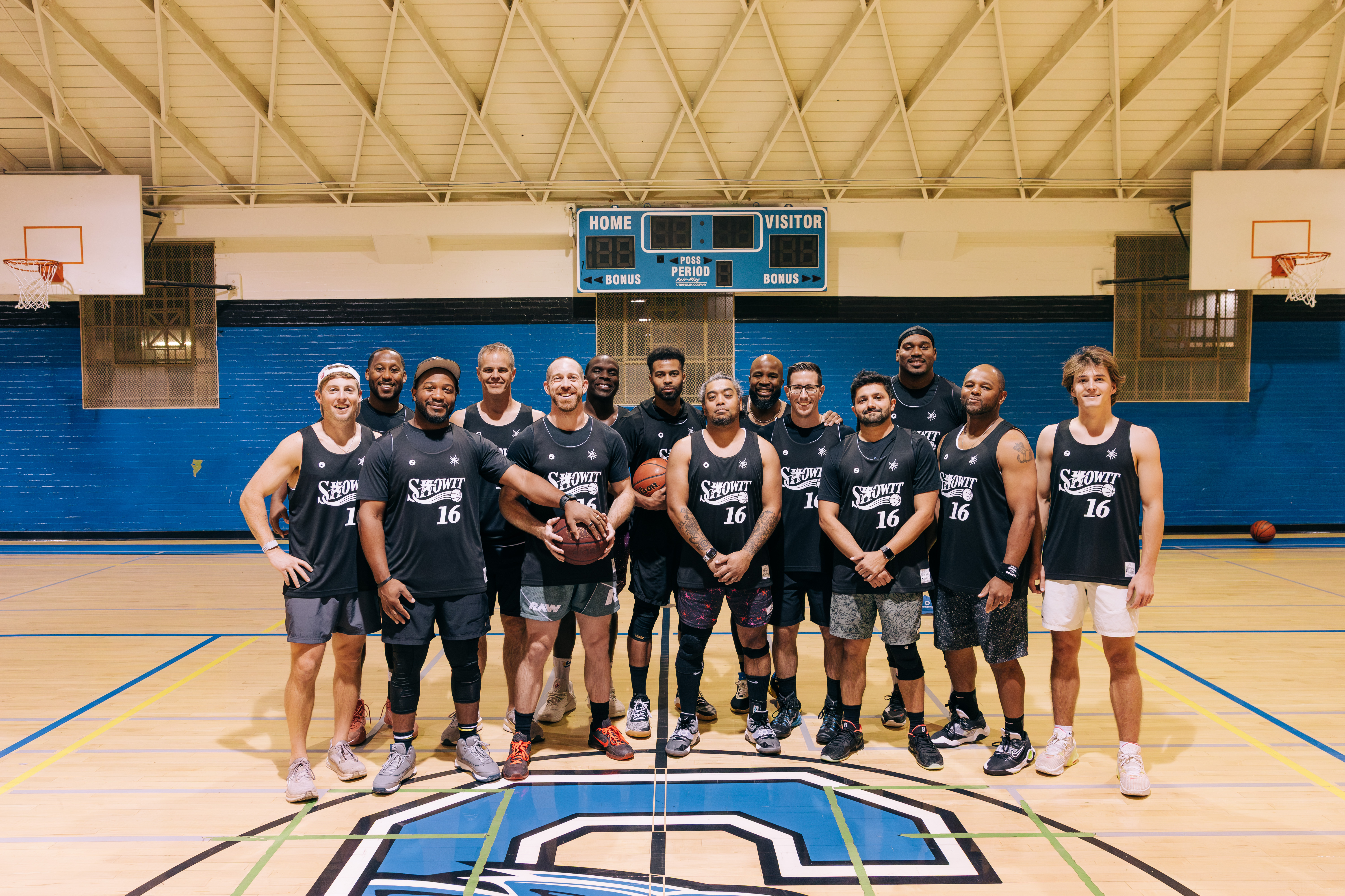14 guys posing for photos on a basketball court