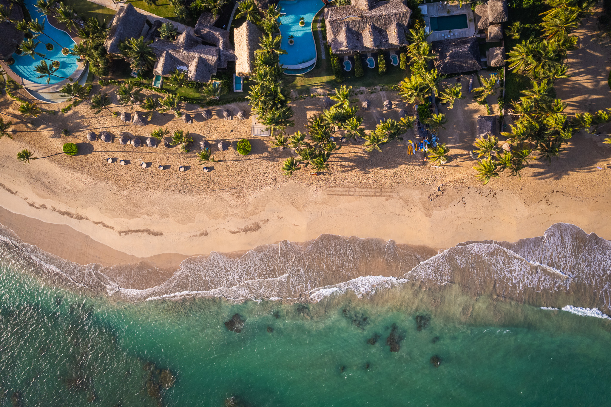 Drone shot of resort, showing beach and pools