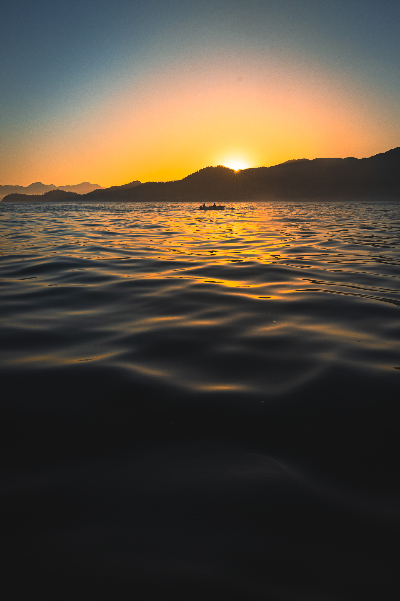 Sunrise on the water with a lone boat in the foreground